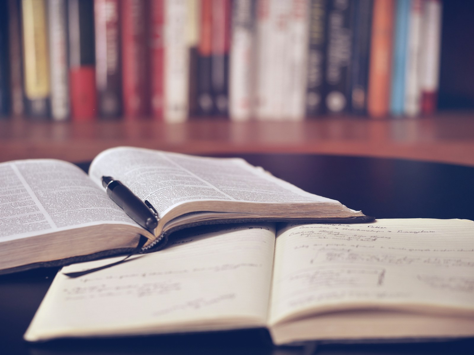 An open book, a pen, and a notebook on a desk